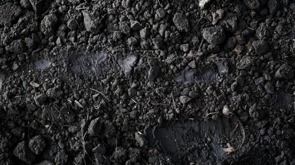 A close up of a black dirt ground with a footprint in it
