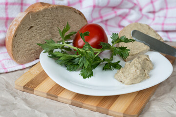 Aubergine cream on a white plate with bread and tomatoes.