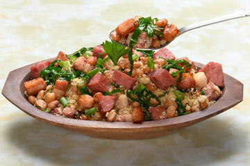 Tropeiro beans in a wooden container, typical food from Minas Gerais, Brazil, yellow marble background
