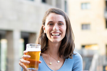 Enjoying a cold beer on a sunny day. A young woman's candid moment of happiness, perfectly capturing the essence of urban leisure.