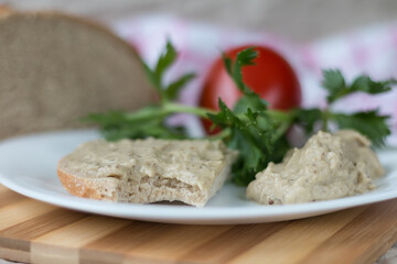 Aubergine cream on a white plate with bread and tomatoes.