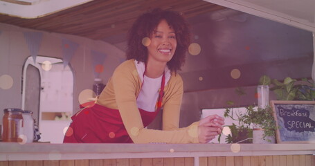 Image of yellow dots over happy biracial waitress looking at camera - Powered by Adobe