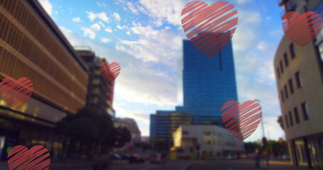 Image of red hearts falling over cityscape