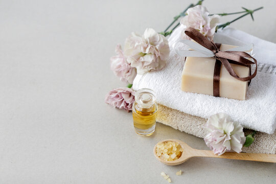 A bar of handmade soap on the towel. Other spa cosmetics around.