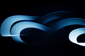 Blue neon curved wave of light as curls or swirl with smooth stripes on black background, pattern. Abstract background with motion light effect, light painting in holiday style. - 785443925