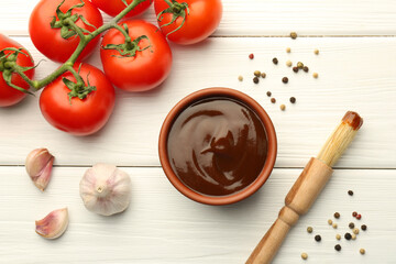 Flat lay composition with tasty barbeque sauce in bowl on white wooden table
