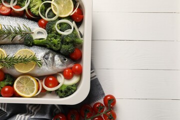 Raw fish with vegetables and lemon in baking dish on white wooden table, flat lay. Space for text