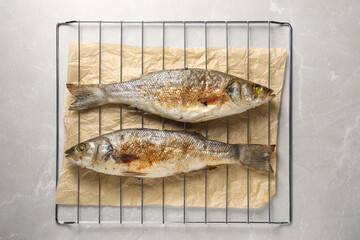 Baked fish on light marble table, top view