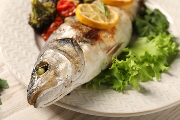 Delicious baked fish and vegetables on table, closeup