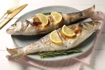 Delicious baked fish served on white wooden table