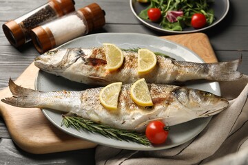 Delicious baked fish served on grey wooden table