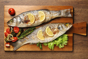 Delicious baked fish and vegetables on wooden table, top view