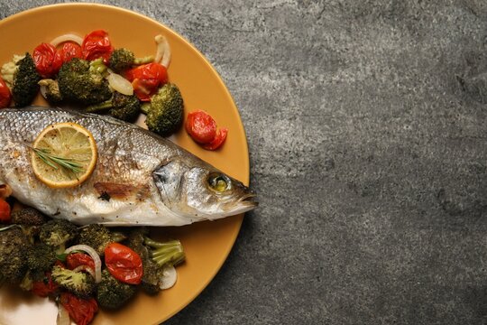 Delicious baked fish and vegetables on grey background, top view. Space for text
