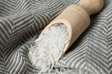 Raw basmati rice in scoop on fabric, closeup