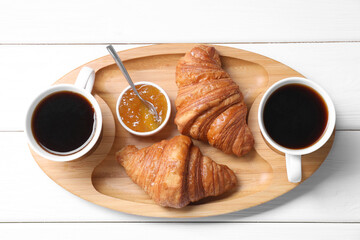 Tasty breakfast. Cups of coffee, jam and croissants on white wooden table, top view