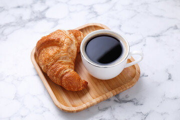 Tasty breakfast. Cup of coffee and fresh croissant on white marble table