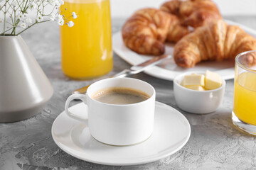Tasty breakfast. Cup of coffee, butter and fresh croissants on grey table, closeup