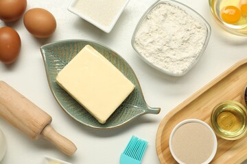Flat lay composition with fresh butter among other products on white table