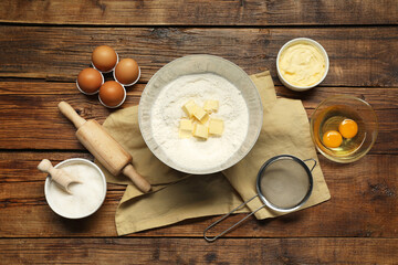 Flat lay composition with fresh butter and flour in bowl among other products on wooden table
