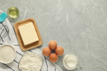 Flat lay composition with fresh butter and other products on grey marble table. Space for text