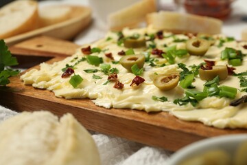 Fresh butter board with cut olives, onion and sun-dried tomatoes on table, closeup