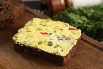 Tasty butter with green onion, chili pepper and rye bread on wooden board, closeup
