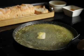 Melting butter in frying pan on cooktop, closeup
