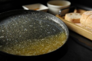 Melted butter in frying pan on black table, closeup