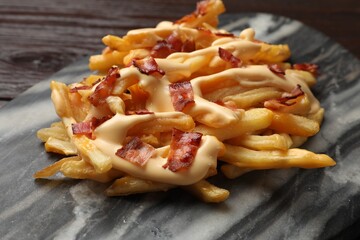 Delicious French fries with bacon and cheese sauce on table, closeup