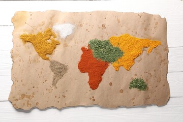 World map of different spices on white wooden table, top view
