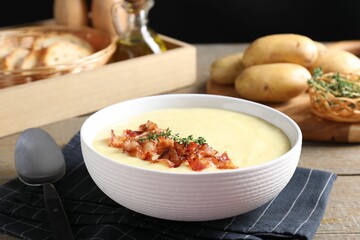 Tasty potato soup with bacon and rosemary in bowl served on wooden table