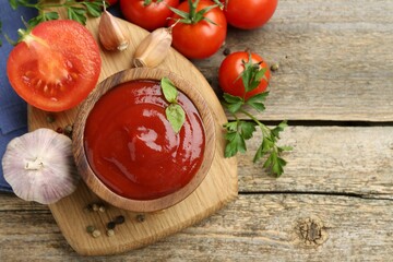 Tasty ketchup, fresh tomatoes, parsley and spices on wooden table, flat lay. Space for text