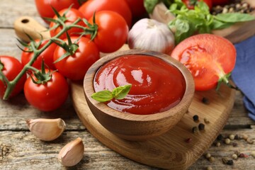 Tasty ketchup, fresh tomatoes, basil and spices on wooden table