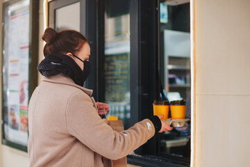 Young woman in mask buying takeaway food