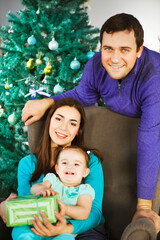 Family with Christmas present near the Christmas tree