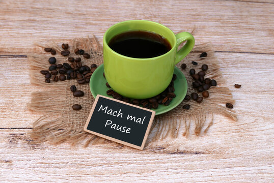  Vor einer Tasse Kaffee steht ein Schild mit der Aufschrift mach mal Pause.