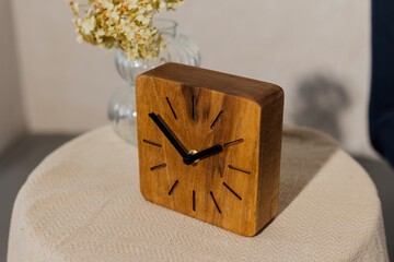 Walnut wall clock. Dry flowers in a vase on the table.