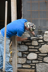 muratore al lavoro costruzione muro di pietra 