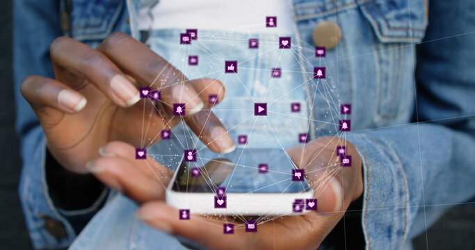 Image of connected icons forming globe over midsection of african american woman using cellphone