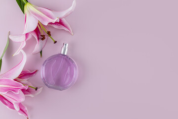 luxury round bottle of women's perfume on pastel background with garden delicate lilies. Presentation of a floral fragrance. Top view. A copy space