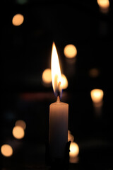 Close-up of the flame of candle in the dark in church with bokeh background. Candle light with copy space.