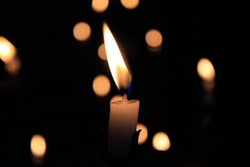Close-up of the flame of candle in the dark in church with bokeh background. Candle light with copy...