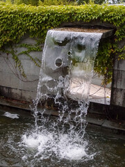 Close-up view of a cascading feature water fountain in a public park. Powerful spout of cascading...