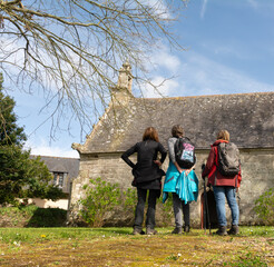 Des randonneuses qui admirent l'architecture extérieure de la chapelle de la Salle de Lanmérin en Bretagne