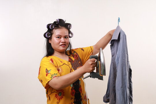 Asian housekeeper woman standing while holding an iron and clothes