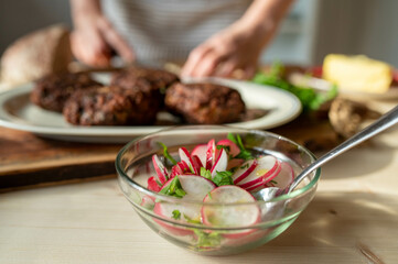 Bowl with fresh radish salad marinated with olive oil and parsley on kitchen table