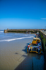 A view along an inner harbour wall at low tide in Saundersfoot, Wales on a bright spring day