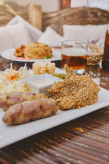 A plate of food with a side of potatoes and a dipping sauce. blackened guinea pig, Peruvian food.