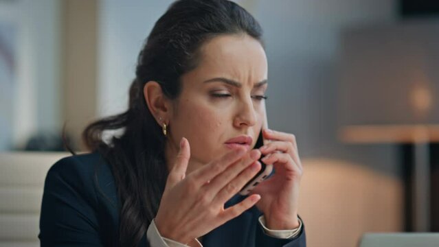 Stressed businesswoman speaking phone gesturing hand at office desk closeup