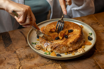 woman eating cake with dried apricots, raisins and walnuts on grey background